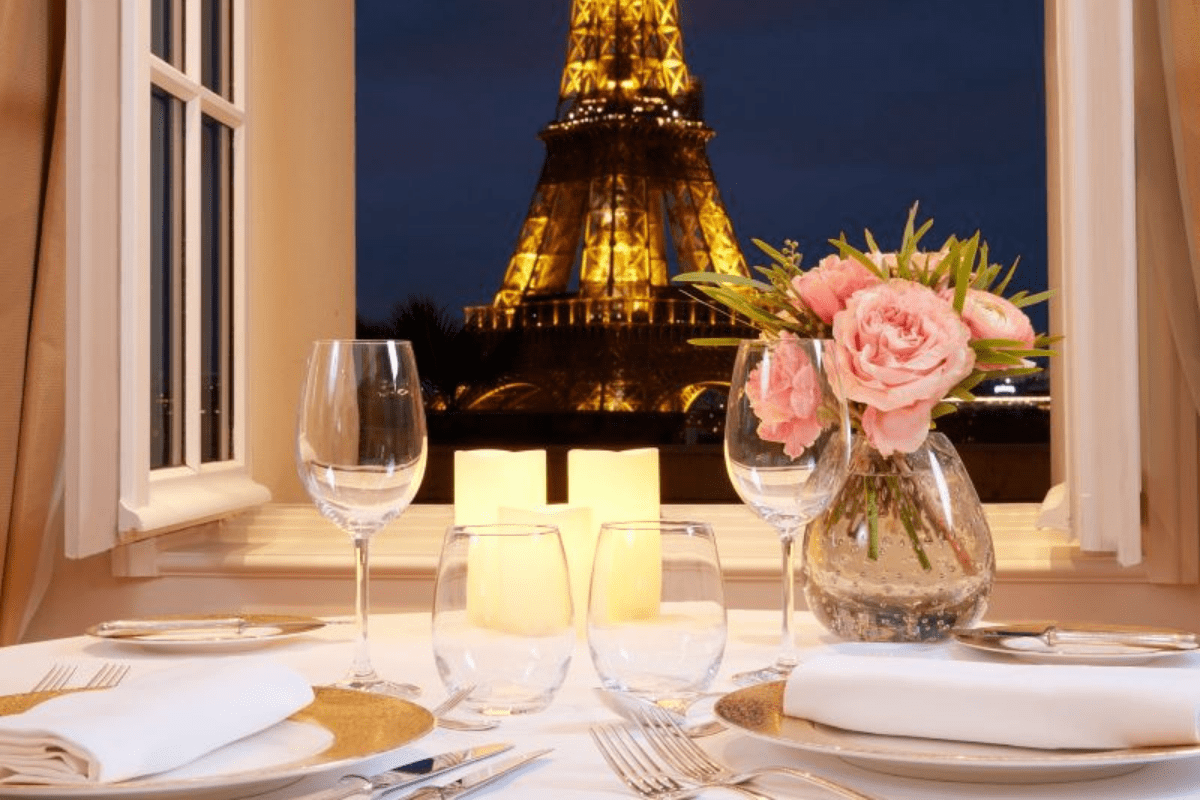 Table dressée dans un restaurant avec vue sur la Tour Eiffel illuminée